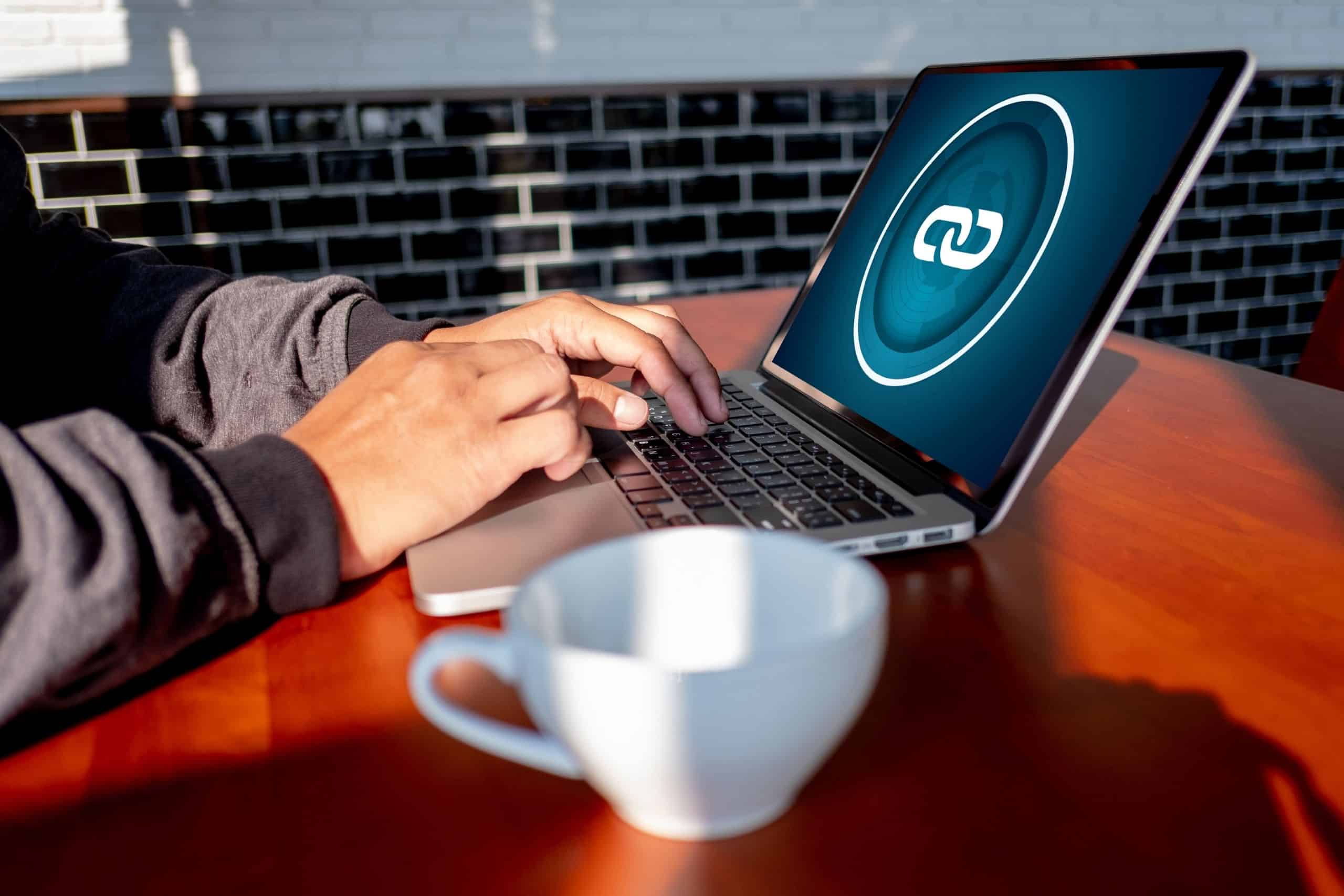In-Content Link Services San Diego - man working on laptop on table with backlink icon and network displayed - Ascendance Website Solutions