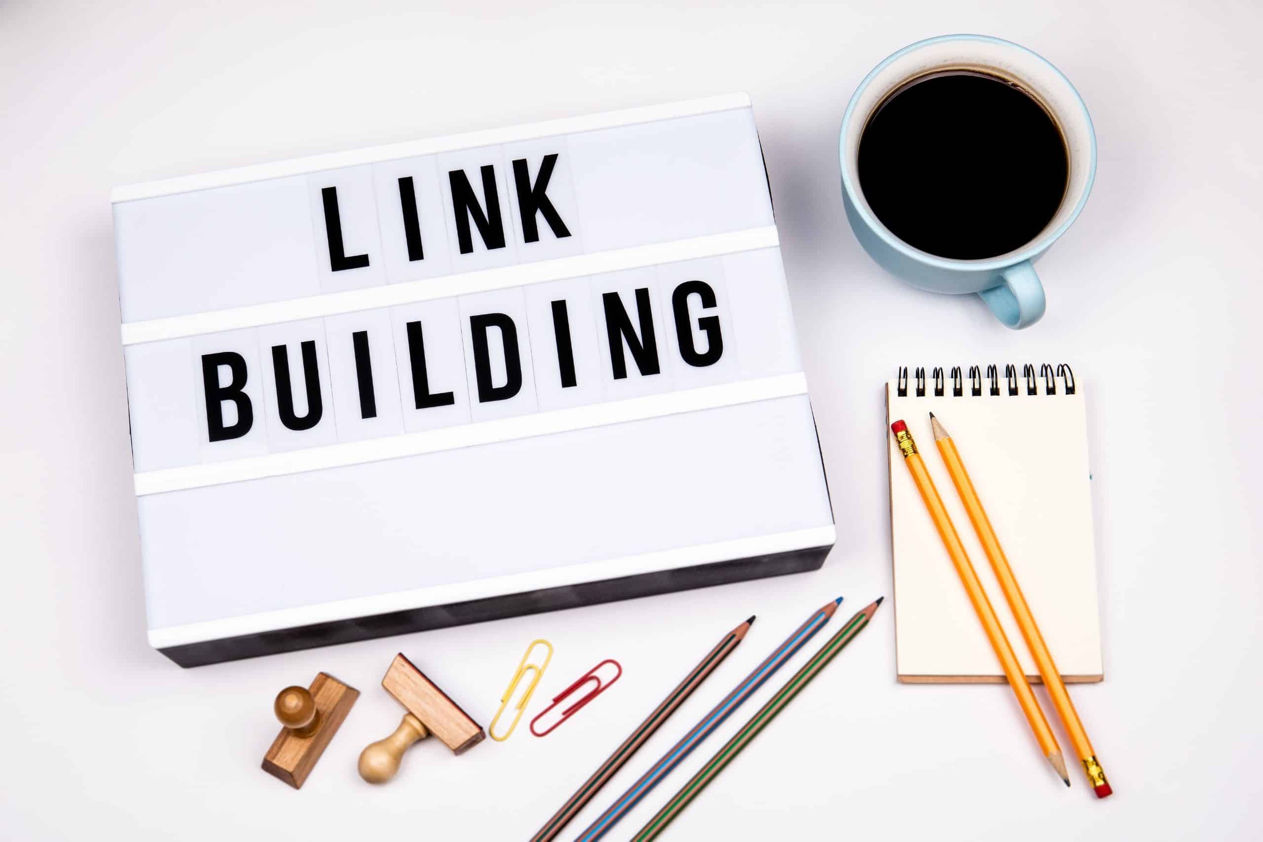 In-Content Link Services San Diego - table with coffee, pencils, pad, clips and board that says link building - Ascendance Website Solutions