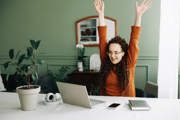 photo of woman on laptop celebrating after using advanced tactics for email marketing for consulting firms